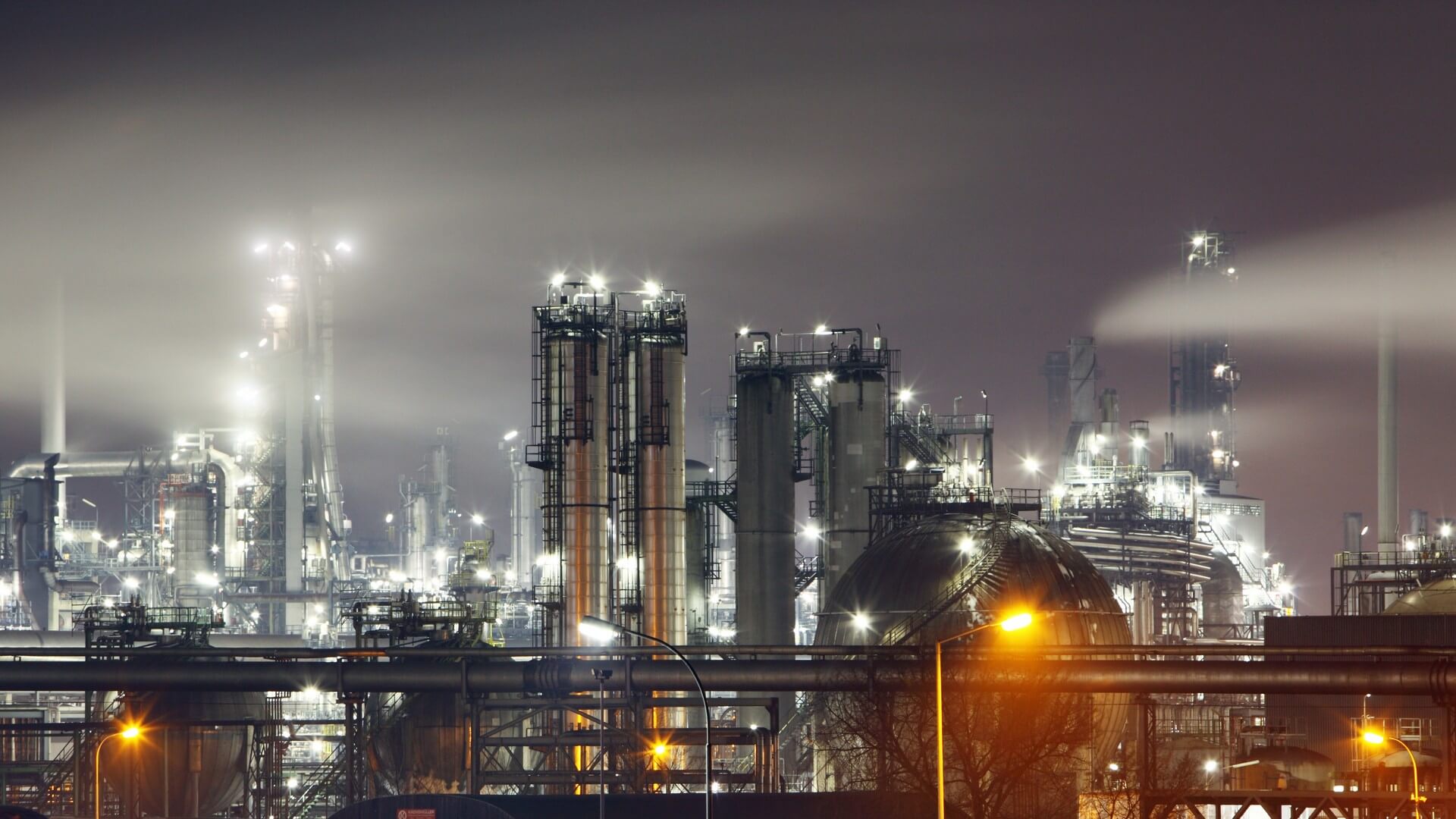 A large industrial area with many lights and pipes.