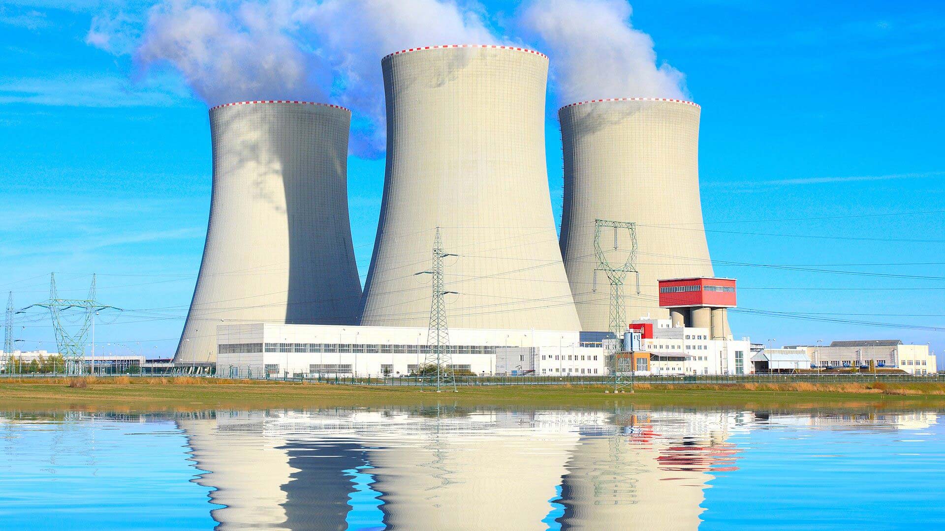 A large white building with three cooling towers.