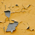 A yellow wall with peeling paint on it.