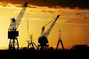 A group of cranes in the middle of an industrial area.